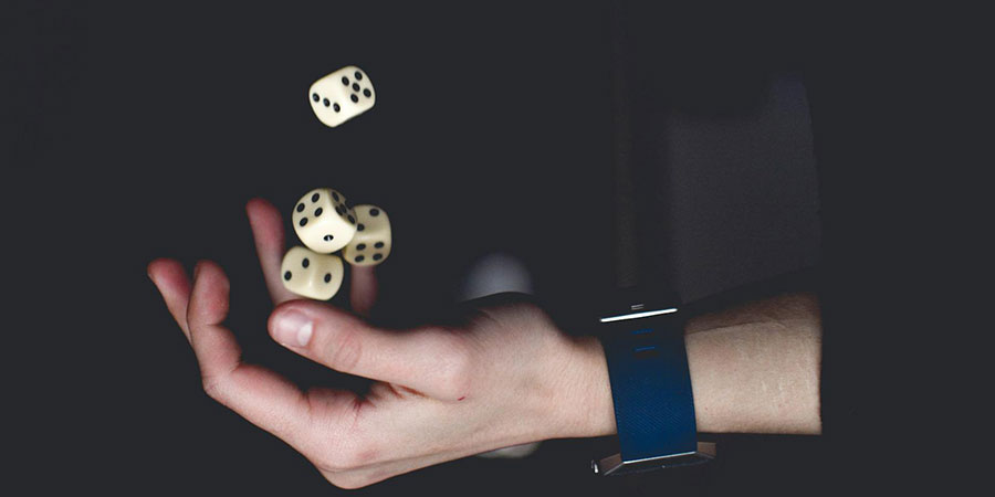 close up view of a person's hand playing with dice and about to catch them in the air